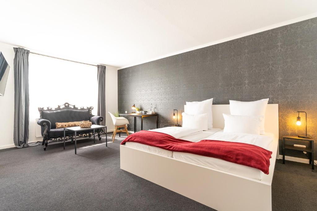a bedroom with a large bed with a red blanket at Schäfers Hotel in Cloppenburg