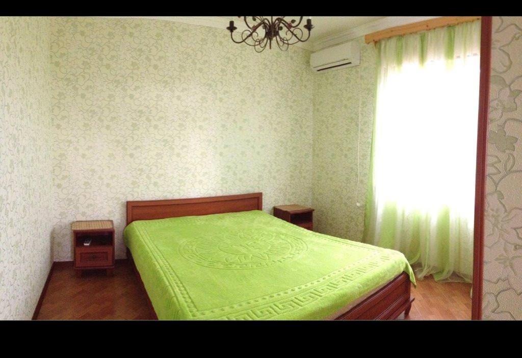 a bedroom with a green bed and a window at Гостевой дом in Gagra