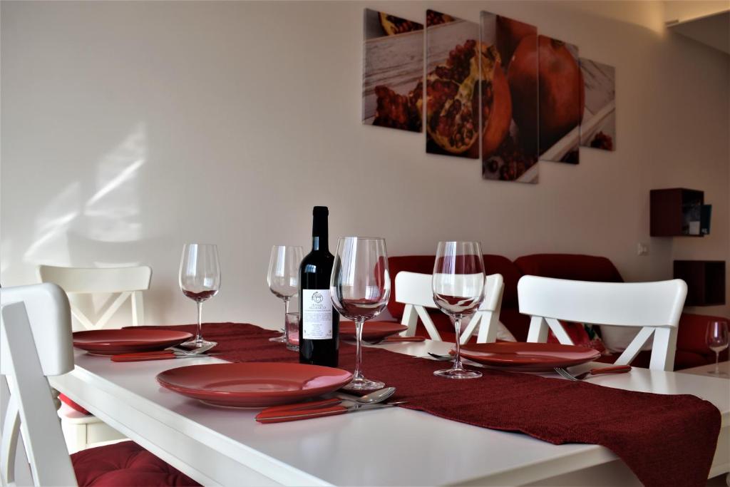 einen weißen Tisch mit roten Platten und eine Flasche Wein in der Unterkunft Melograno Home in Neapel
