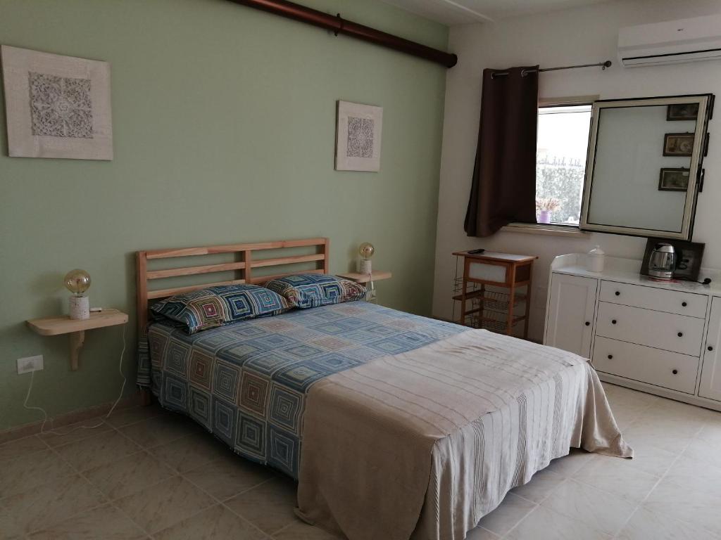 ein Schlafzimmer mit einem Bett, einer Kommode und einem Fenster in der Unterkunft El Paso in Castro di Lecce