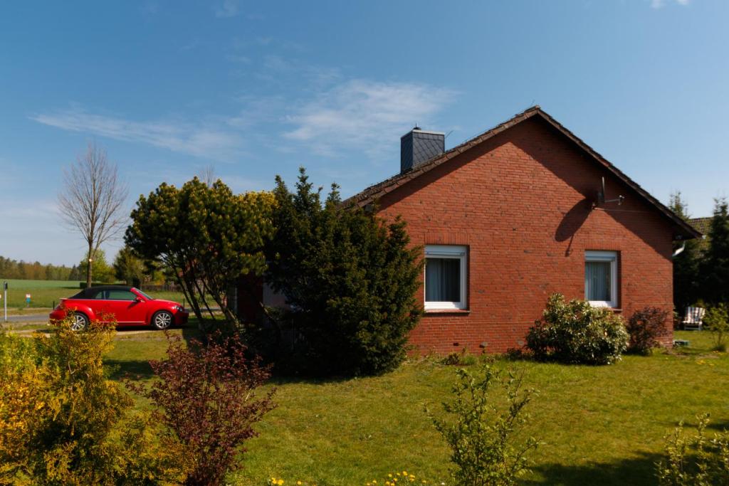 une voiture rouge garée devant une maison en briques dans l'établissement Haus Schneverdingen, à Schneverdingen