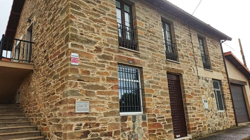 Casa Santiago في Currelos: مبنى من الطوب القديم مع نوافذ سوداء