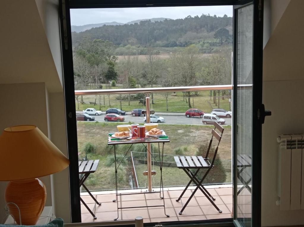 een balkon met een tafel en stoelen en uitzicht op een parkeerplaats bij Costa da Morte "Paraiso de Galicia" in Ponteceso