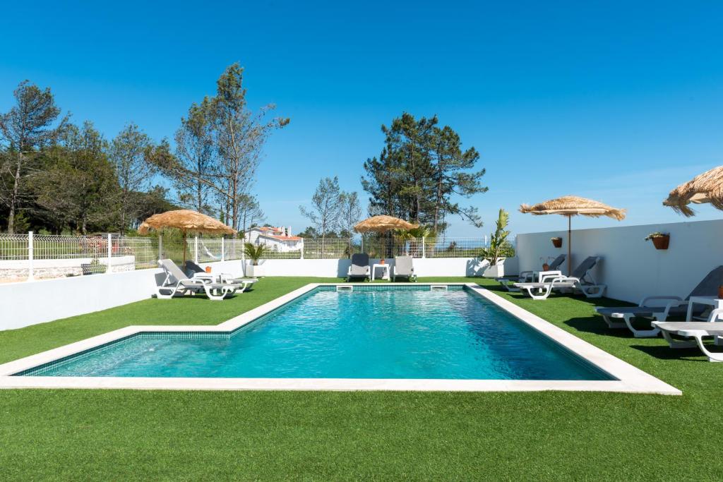 einen Pool im Garten mit Stühlen und Sonnenschirmen in der Unterkunft Quinta Bogesi in Figueira da Foz