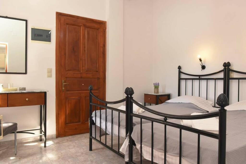 a bedroom with a black bed and a wooden door at Atropos Varvara in Posidhonía