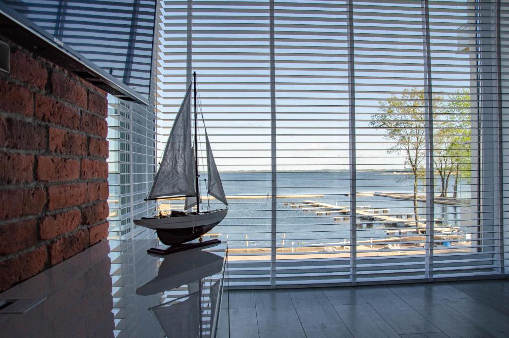 a model boat on a table in front of a large window at nauticaluxapartamenty.pl in Giżycko