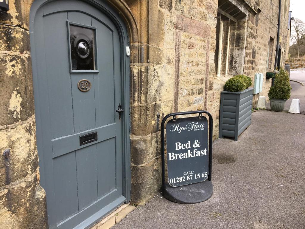 a sign in front of a building with a door at Rye Flatt Bed and Breakfast in Colne