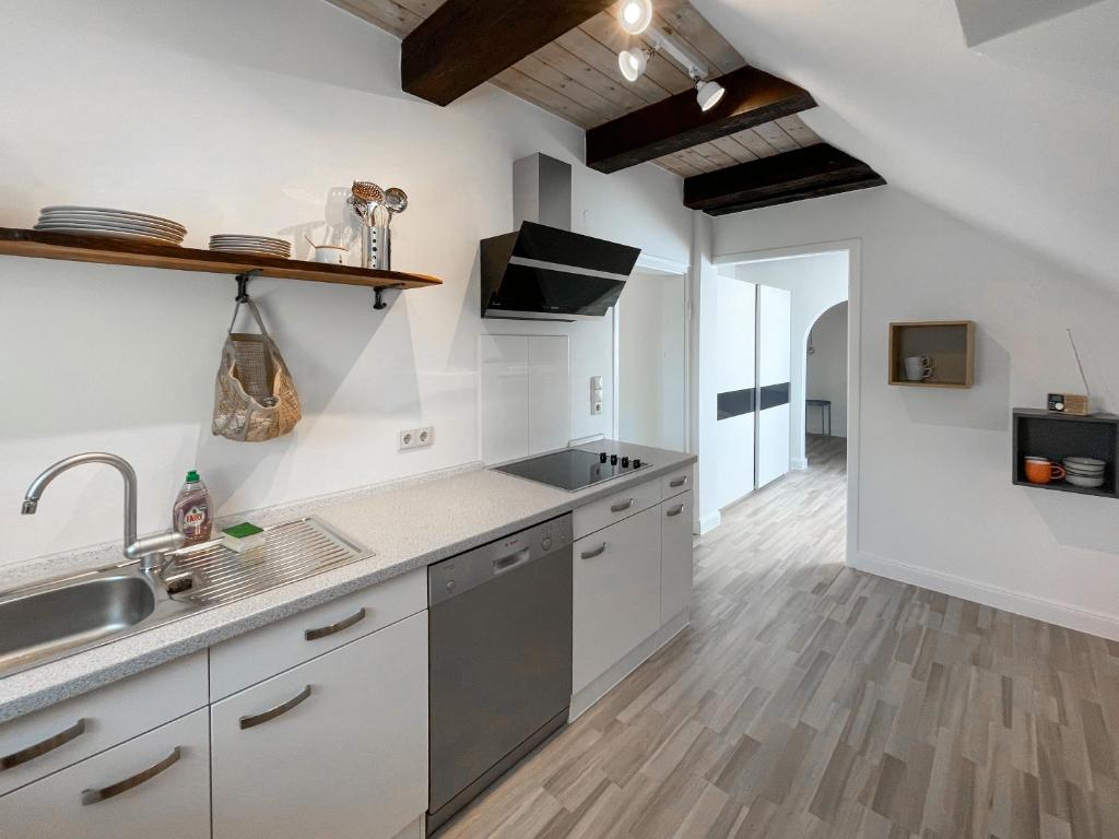 a kitchen with white cabinets and a sink and wooden floors at Pauernhof Ferienwohnungen in Bad Nenndorf