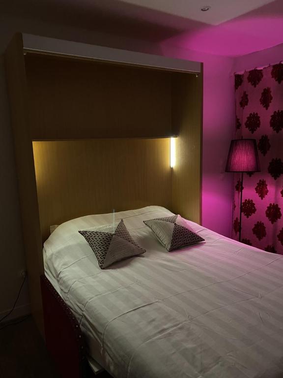 - une chambre avec un grand lit blanc et un éclairage violet dans l'établissement L'échappée Bordelaise, à Portets