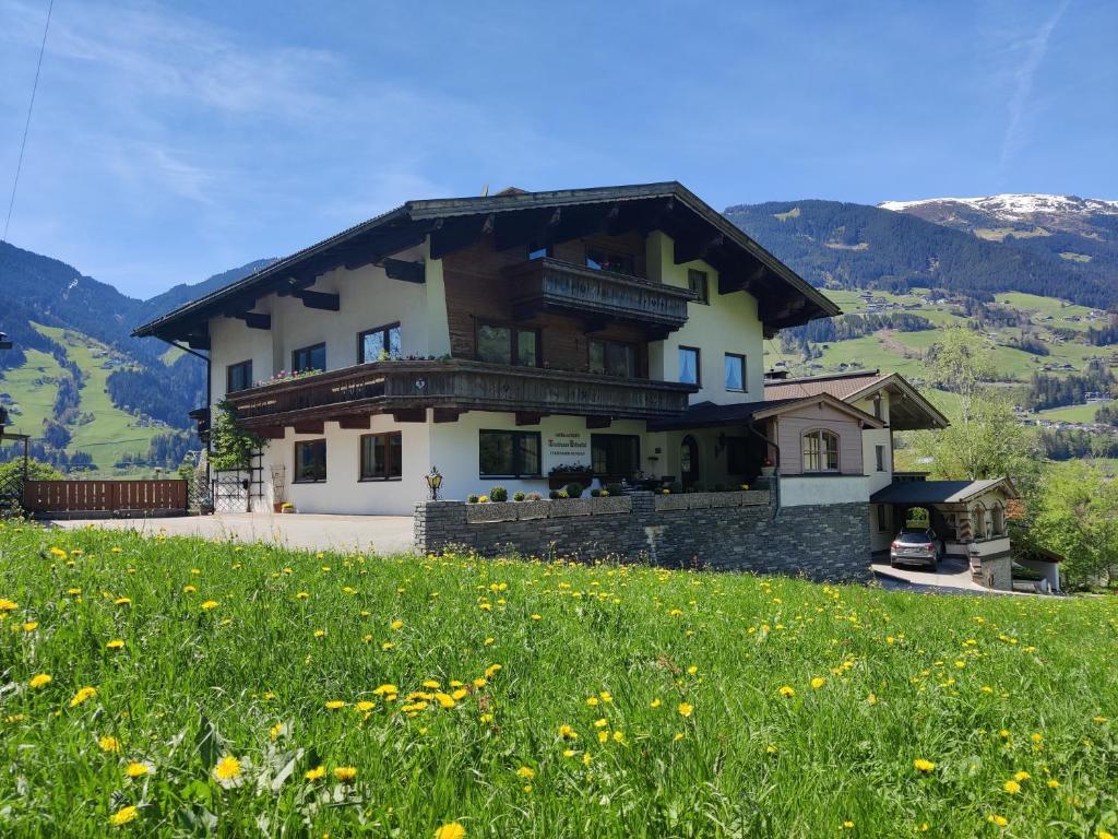 une maison sur une colline avec un champ de fleurs dans l'établissement Landhaus Zillertal, à Ramsau im Zillertal