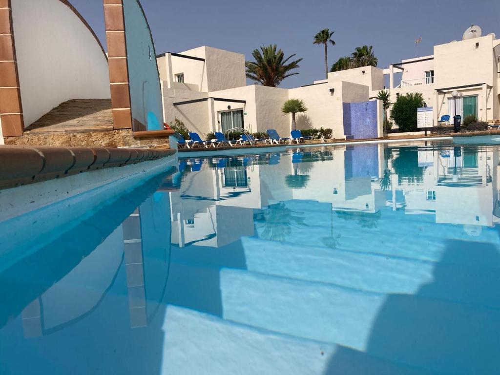 einen Pool mit blauem Wasser und blauen Stühlen in der Unterkunft Alisios Dream in Corralejo