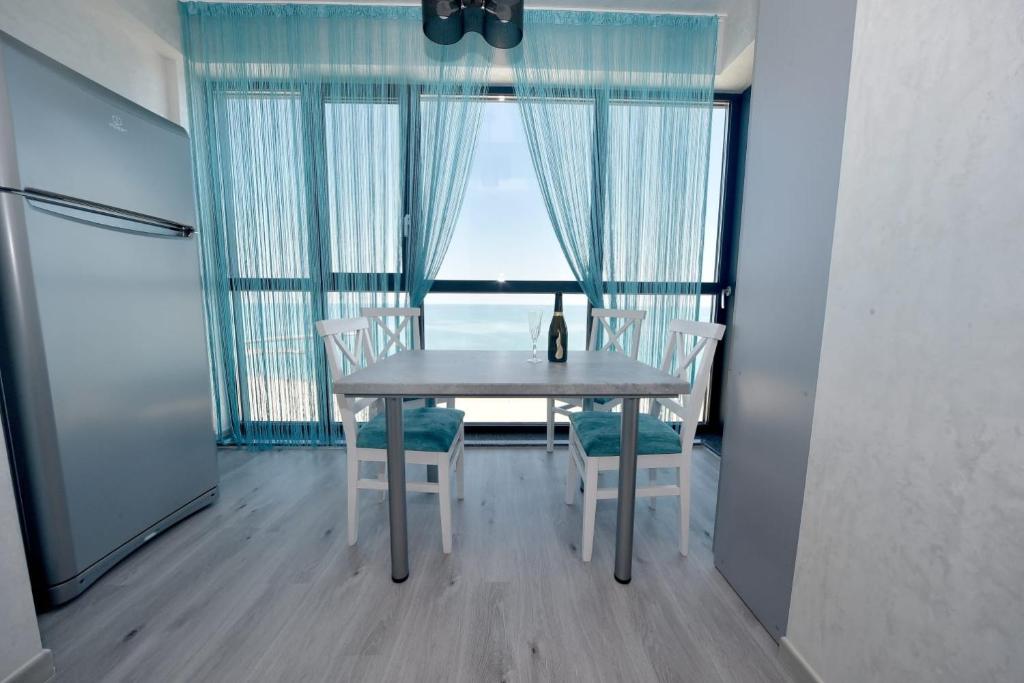 a table and chairs in a room with a window at Turquoise by the sea in Constanţa