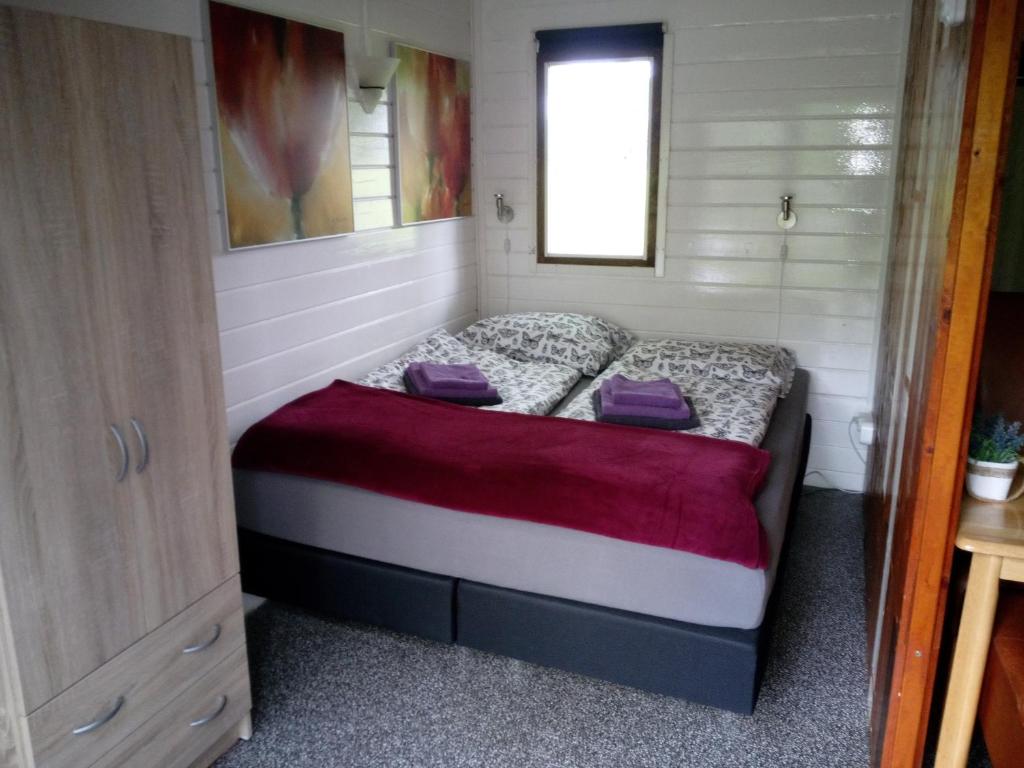 een kleine slaapkamer met een bed in een tiny house bij Blokhut De Vlinder gelegen nabij het Pieterpad in Coevorden
