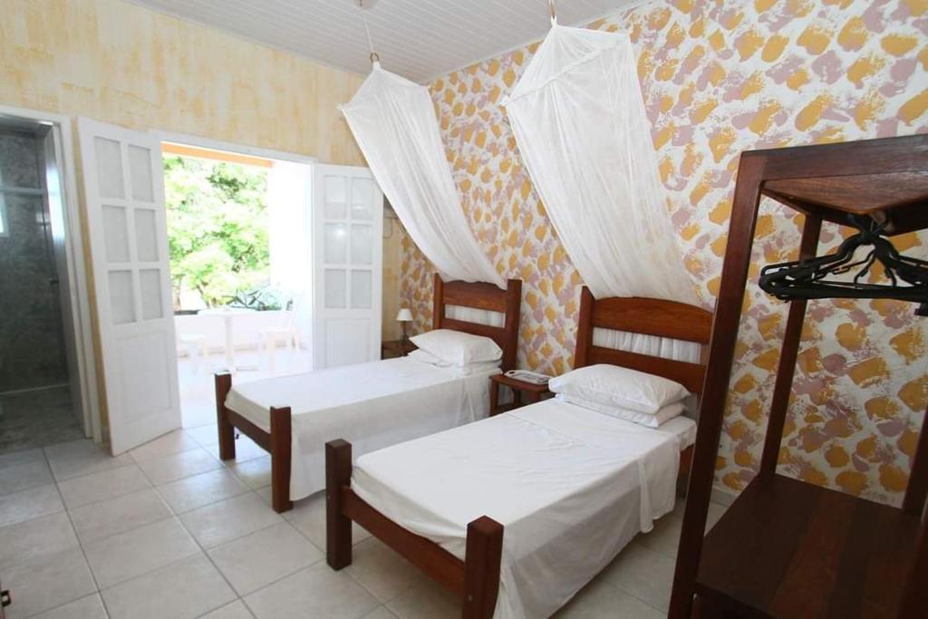 sypialnia z 2 łóżkami i oknem w obiekcie Pousada Canavieiras Frederic w mieście Canavieiras