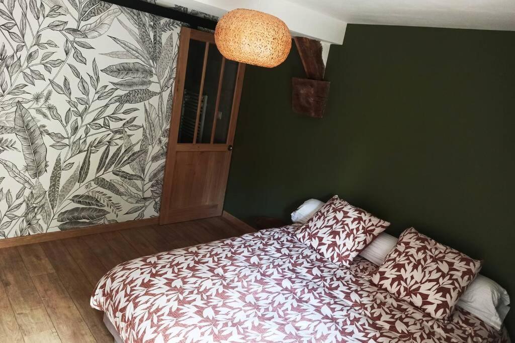 a bedroom with a bed and a green wall at Gîte Le Tico in Cheverny