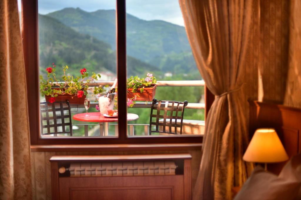 uma vista a partir de uma janela de uma mesa com flores numa varanda em Mountain Boutique Family Hotel em Devin