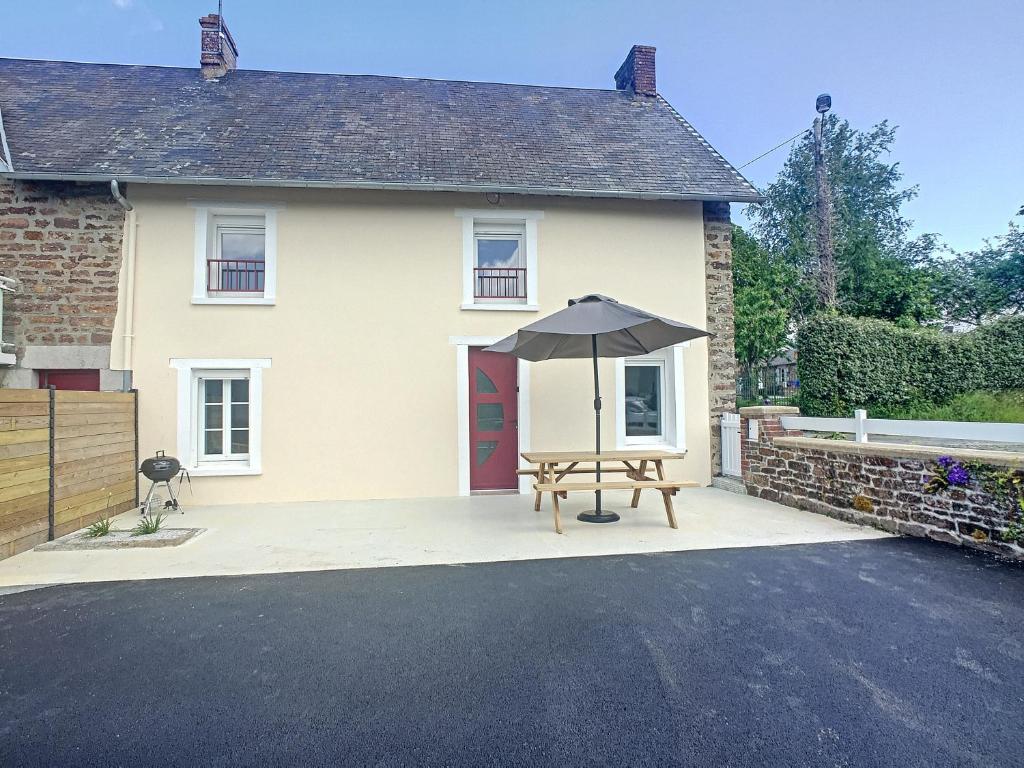 une table avec un parasol devant une maison dans l'établissement petite maison proche centre ville, à Bréhal