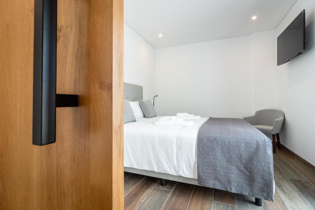 a bedroom with a bed and a tv on a wall at Roots Hotel in Faro