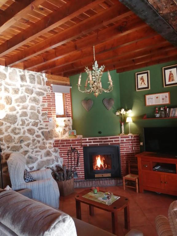 a living room with a fireplace and a stone wall at El Mirador del Gato I y II in Mesegar de Corneja