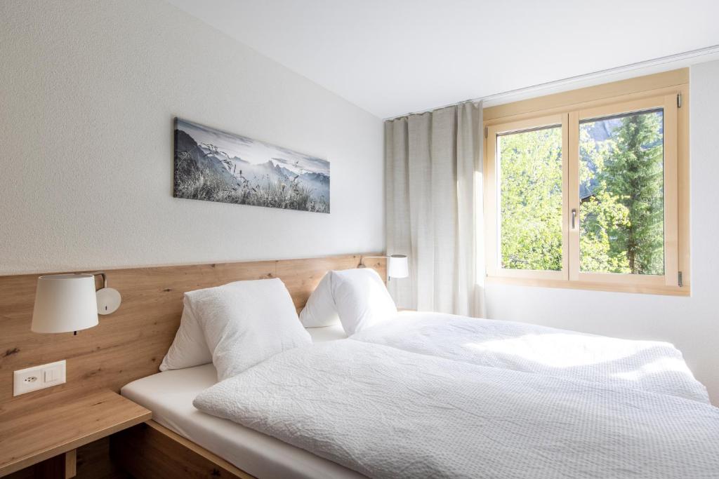 a bedroom with a white bed and a window at Hotel Restaurant Urweider in Innertkirchen