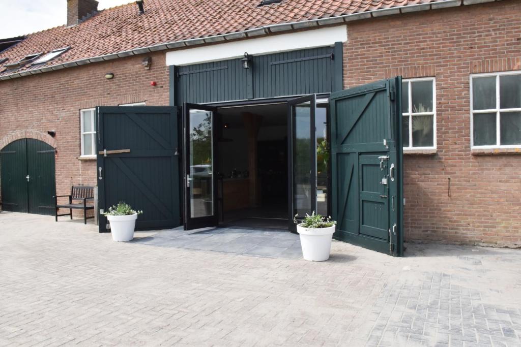 una puerta abierta de un edificio de ladrillo con macetas en ZeeLand & Meer en Kamperland
