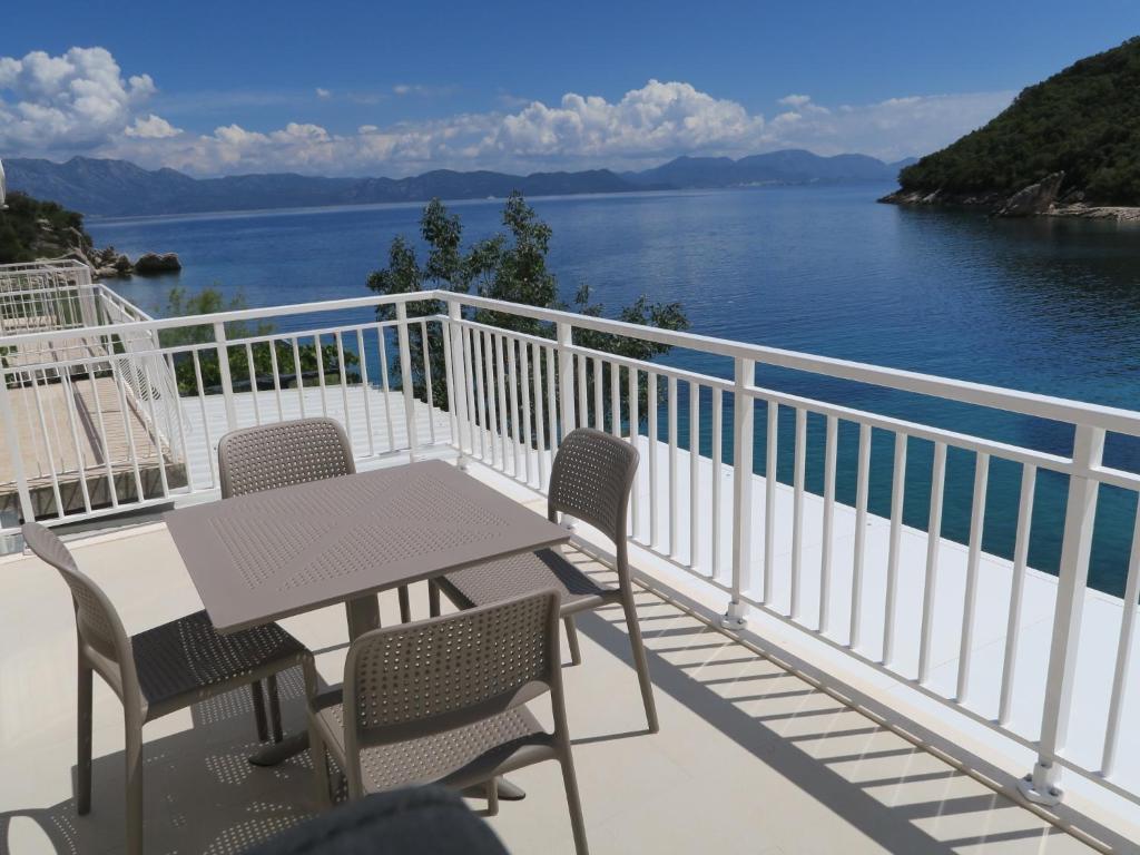 a table and chairs on a balcony with a view of the water at Old Fisherman's House w 3BD, balcony and terrace by the Sea in Oskorušno