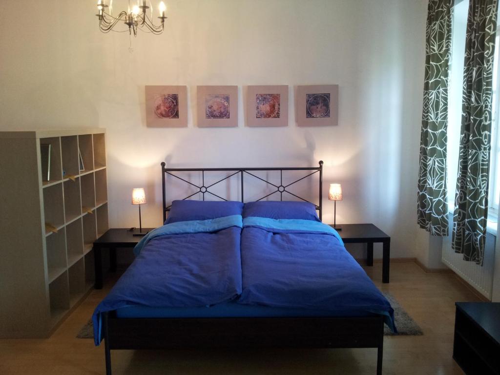 ein Schlafzimmer mit einem Bett mit blauer Bettwäsche und zwei Lampen in der Unterkunft Studio Ian 1 in Ljubljana
