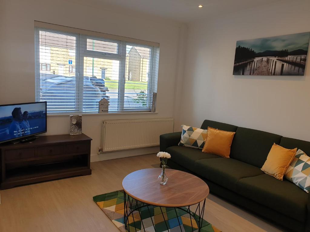 uma sala de estar com um sofá verde e uma mesa em JDB Dartford 2-Bedroom House em Dartford