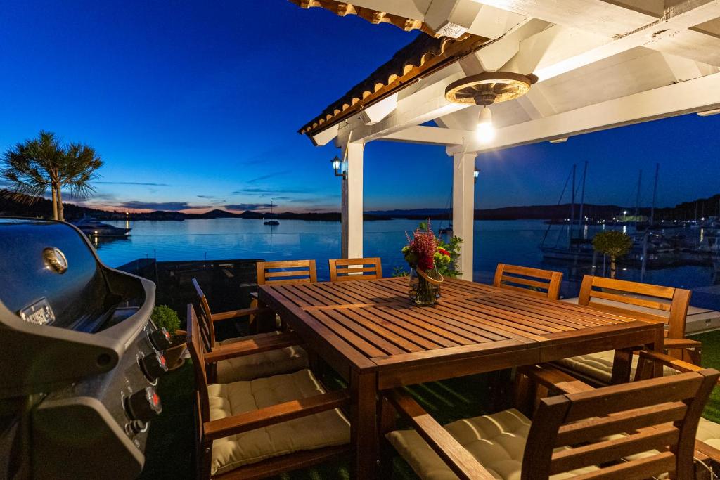 - une table en bois sur une terrasse avec vue sur l'eau dans l'établissement Luxury LeNi Guest House, à Murter