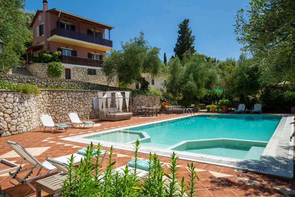 a swimming pool in a yard with chairs and a building at Evridiki's Villas in Agios Nikitas