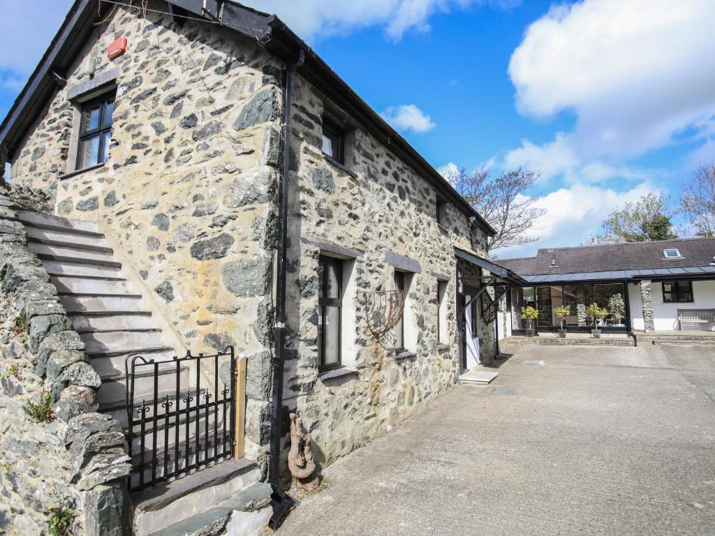 an old stone building with a stone wall at Bryn Eira Stables in Llanfairpwllgwyngyll