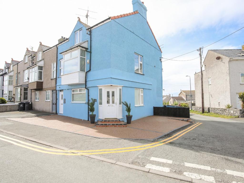 een blauw huis aan de kant van een straat bij Twyni Bach in Rhosneigr