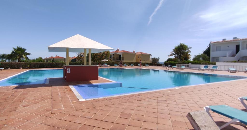 uma grande piscina com guarda-sol e cadeiras em 8 1 Figueirinhas - Casas & Papéis em Armação de Pêra