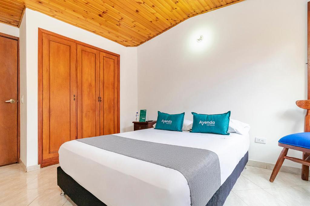 1 dormitorio con 1 cama blanca grande con almohadas azules en Ayenda Hotel Casona Santa Rosa, en Chía