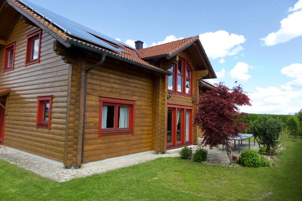 ein Holzhaus mit roten Fenstern und einem Hof in der Unterkunft Holzblockhaus Franziska in Plattling