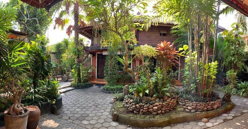 un patio con árboles y plantas frente a una casa en The Arya guest house, en Gilimanuk