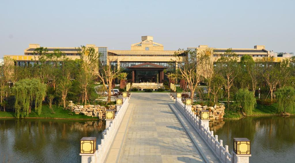een loopbrug voor een gebouw naast een meer bij Wuxi Yew Resort in Wuxi