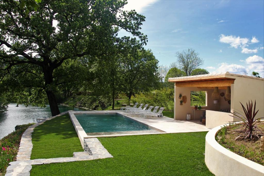 a swimming pool in a yard next to a house at La Magnanerie d'Hôtes ,le jardin secret in Sauve