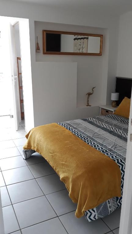 - une chambre avec un lit et une couverture jaune au sol dans l'établissement Villa Moris, à Dolus-d'Oléron