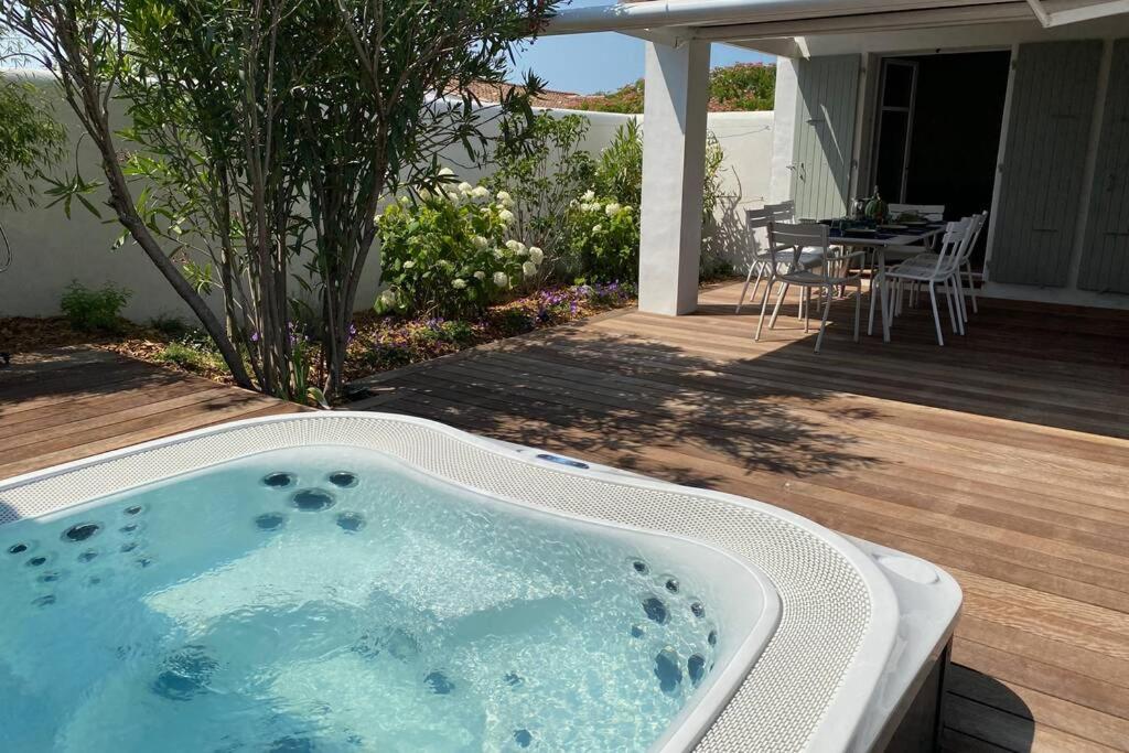 un bain à remous sur une terrasse en bois avec une table dans l'établissement Elégante maison d'architecte, Spa à débordement, à La Noue