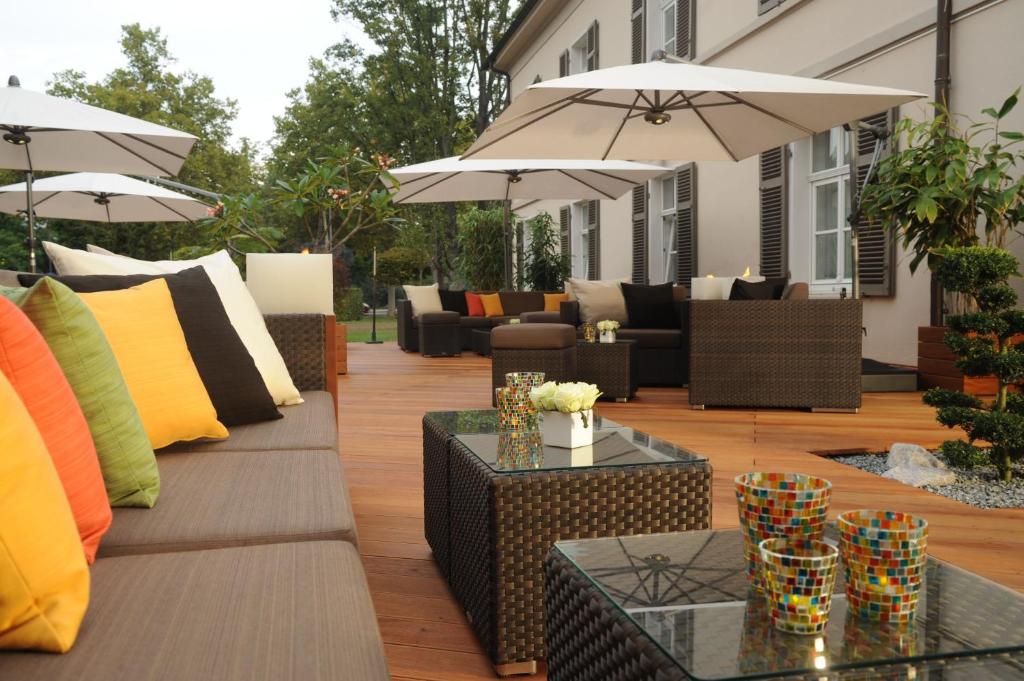 patio z kanapami, stołami i parasolami w obiekcie René Bohn w mieście Ludwigshafen am Rhein