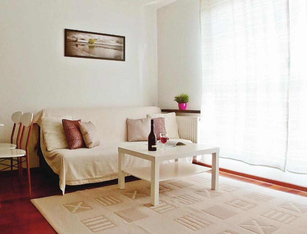 a living room with a white couch and a table at Apartament Bello - free parking in Gdańsk