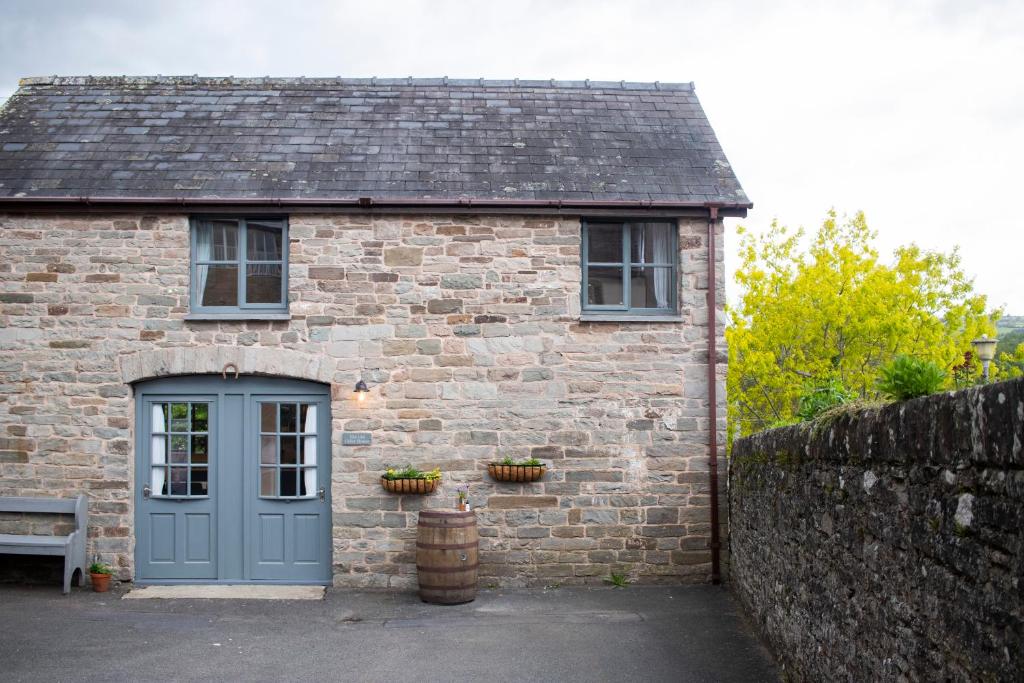 uma casa de tijolos com uma porta azul e um banco em The Old Cider House em Hay-on-Wye