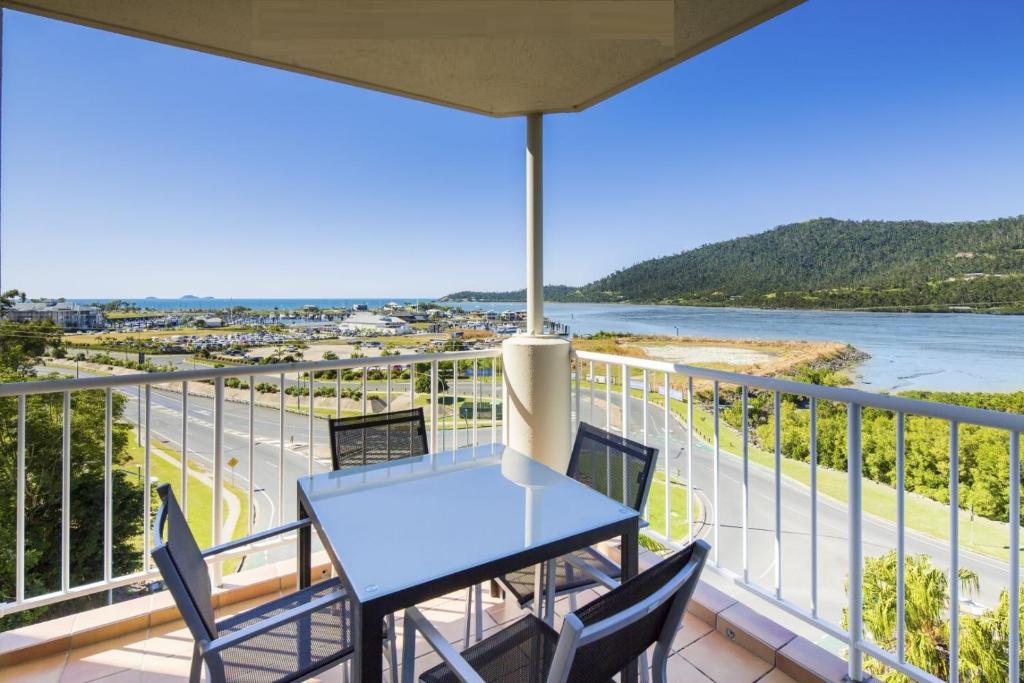 a table and chairs on a balcony with a view of the ocean at ☆Airliedise☆NO hills☆Kitchen☆5min walk 2 Ferry terminal☆WiFi☆Netflix in Airlie Beach