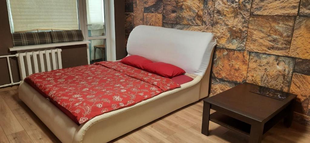 ein Bett mit roten Kissen und einem Tisch in einem Zimmer in der Unterkunft Тихий lux, левый берег, Караван in Nizhnedneprovsk