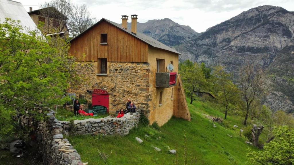 ein Haus auf einem Hügel mit Leuten draußen in der Unterkunft Le Seuil De Mes Reves in Le Lauzet-Ubaye