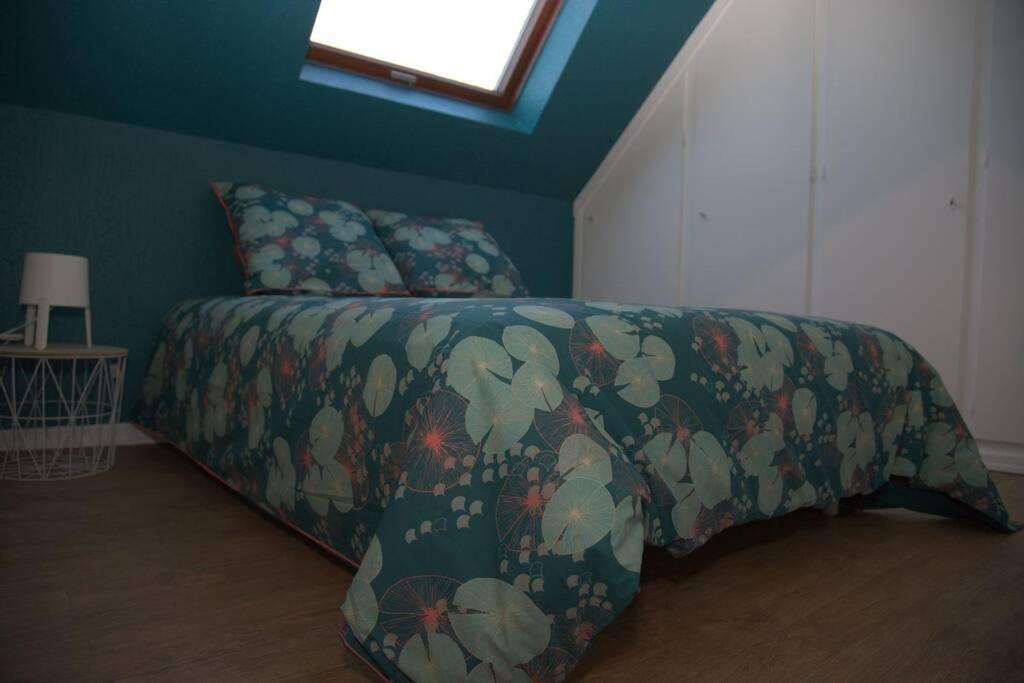 a bedroom with a bed with a flowered blanket and a window at Gîte alsacien in Eckwersheim