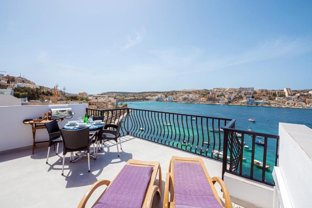 a balcony with a table and chairs and a view of the water at Harbour Lights Seafront Penthouse, with large terrace with stunning panoramic sea views - by Getawaysmalta in St Paul's Bay