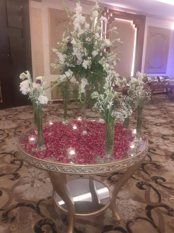 a table with vases of flowers on it at Hotel Gulberg Lodges Hali Road in Lahore