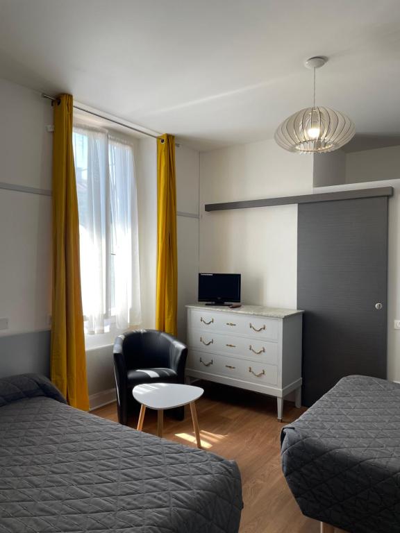 a bedroom with two beds and a desk and a chair at Hôtel du Clos Fleuri in Lourdes